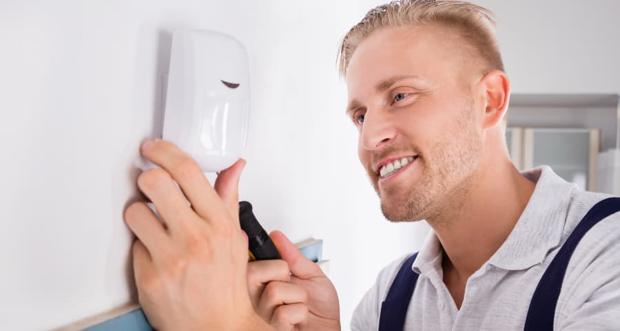 Man installing a motion sensor on a wall